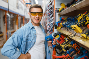 Wall Mural - Buyer holding electric screwdriver, hardware store