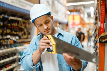 Wall Mural - Male customer choosing saw in hardware store