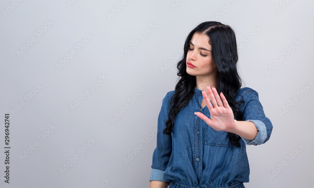 Young woman making a rejection pose on a gray background - obrazy, fototapety, plakaty 