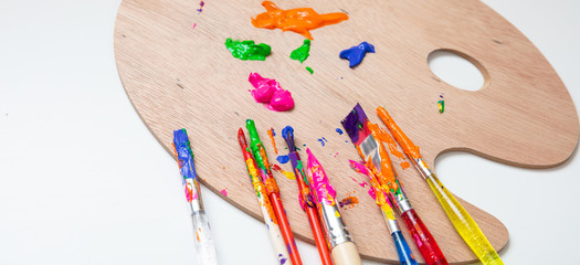 Wall Mural - Paintbrushes, colorful paints and wood palette on white color background