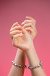 © mathefoto - Closeup image of beautiful woman's hands with light pink manicure on the nails on the isolated pink background. Cream for hands , manicure and beauty treatment.