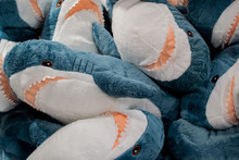 A Lot Of Plush Toys In The Form Of Blue And Gray Sharks With Open Jaws With Teeth Piled In A Heap