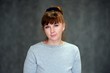 © Вячеслав Чичаев - Close-up portrait of an adult woman with red hair on a gray background in a gray sweater in the studio. Clean face skin, age-related cosmetics.
