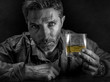 © TheVisualsYouNeed - depressed and thoughtful alcoholic man on his 40s in front of whiskey glass wasted and stressed holding on temptation to drink in alcohol addiction and alcoholism problem