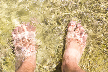 Wall Mural - unfocused bare feet top view in shallow water near shore line summer season sunny vacation time concept poster photography 