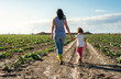 Woman farmer and little girl walking on the agriculture land.