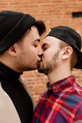 Wall Mural - Two kissing gay men close up standing on the street vertical photo