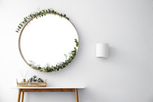 Round Mirror And Table With Accessories Near White Wall In Modern Room Interior