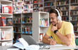 © New Africa - Young man studying at table in modern library