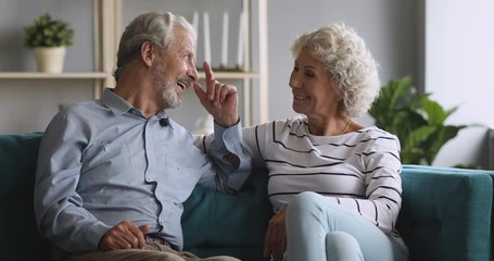 Wall Mural - Happy senior grandparents couple relaxing talking laughing sitting on couch