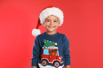 Happy little child in Santa hat on red background. Christmas celebration