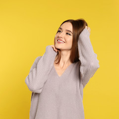 Canvas Print - Beautiful young woman in sweater on yellow background. Winter season