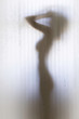 Beautiful naked woman behind a bathroom curtain, perfect female body silhouette.