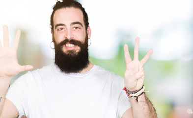 Sticker - Young hipster man with long hair and beard wearing casual white t-shirt showing and pointing up with fingers number eight while smiling confident and happy.