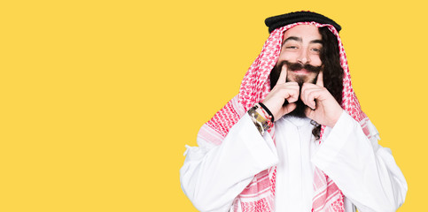 Wall Mural - Arabian business man with long hair wearing traditional keffiyeh scarf Smiling with open mouth, fingers pointing and forcing cheerful smile