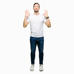 Poster - Handsome man wearing casual white t-shirt relax and smiling with eyes closed doing meditation gesture with fingers. Yoga concept.