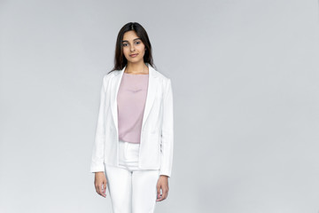 Wall Mural - Photo of successful young adult indian office businesswoman professional corporate teacher saleswoman in white formal wear suit standing isolated on grey background with looking at camera, portrait