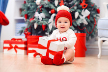 Baby Unpack Gift Boxes With Christmas Decoration, Dressed As Santa, Boke Lights On Dark Background, Winter Holiday Concept