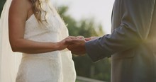 Medium Detail Shot Of Diverse Bride And Groom Holding Hands For Their Wedding Vows At Sunset