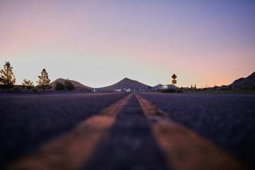 Poster - Low angle shot of an empty road with mountains and a clear sky in the background