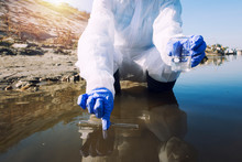 Conserve Water And Environment. Shot Of An Unrecognizable Ecologist Taking Samples Of Water With Test Tube From City River To Determine Level Of Contamination And Pollution.
