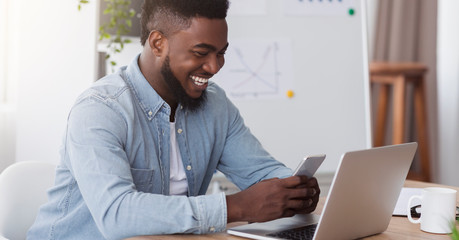 Poster - Happy black manager looking at smartphone screen reading pleasant message