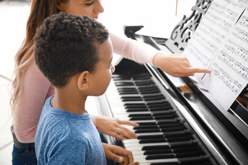 Sticker - Woman teaching little African-American boy to play piano at home