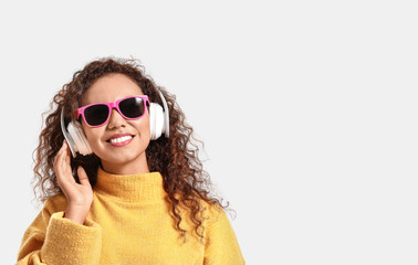 Poster - Beautiful African-American woman listening to music on white background