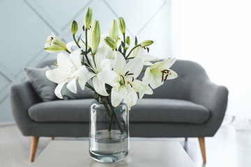 Vase with beautiful lily flowers on table in room