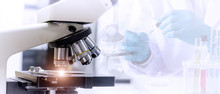 Laboratory Concept:  Close Up Picture Of Microscope With Blurred Background Of Scientist Preparing The Sample For Testing In Laboratory.