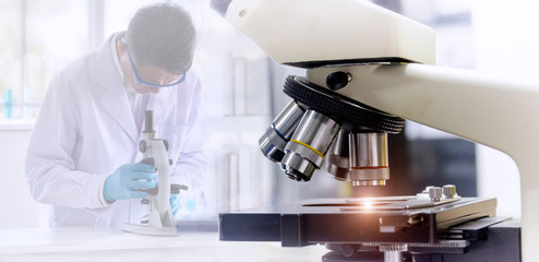 Wall Mural - laboratory concept: close up picture of microscope with blurred background of scientist researching 