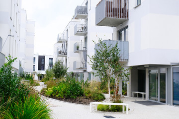 Sidewalk in a cozy courtyard of modern apartment buildings condo with white walls.