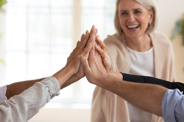 Wall Mural - Happy corporate team with senior mentor give high five, closeup