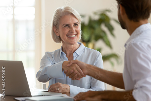 Fotografía Smiling mature saleswoman handshake businessman client customer at business meet