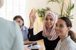 © fizkes - Smiling asian muslim businesswoman raise hand ask question at seminar