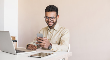 young handsome man using smart phone and laptop at home. businessman or student working on computer 
