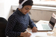 © fizkes - Indian ethnicity woman wearing headphones listens educational course studying online