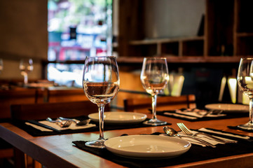 Empty wine glasses, forks and knives close up view on wooden table in restaurant