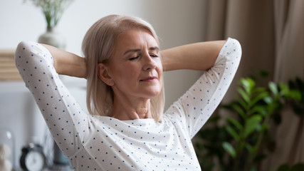 Wall Mural - Calm serene mature woman resting with eyes closed at home