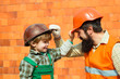 © Tverdokhlib - Happy builders. Protective helmets. Occupational Safety and Health. Family at a construction site. Own house. The American dream. Happy family, father and son.