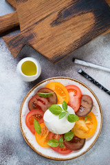 Wall Mural - Caprese salad with various types of tomatoes and mozzarella, flatlay on a beige stone background