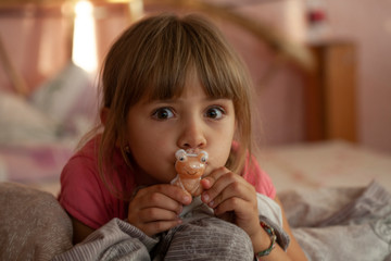 girl sitting looking while tablet. with a toy bear.
