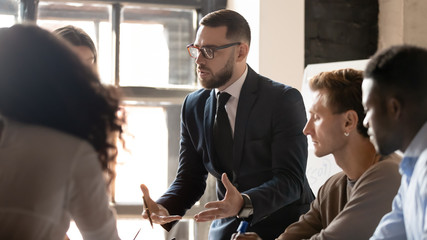 Wall Mural - Serious businessman mentor speaking to diverse people at group training