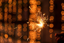 Burning Sparkler Diwali Background Image. Diwali Holiday Greetings Card, Postcard. A Young Woman Holding Lighted Fireworks With Bright Golden Christmas Bokeh Lights. Background Image For Diwali, X-mas