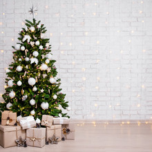 Decorated Christmas Tree, Heap Of Gift Boxes And Copy Space Over White Brick Wall
