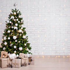 decorated christmas tree, heap of gift boxes and copy space over white brick wall