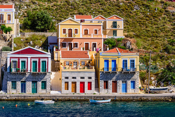 Wall Mural - Sightseeing of Greece. Cityscape of Symi island. Traditional bright facades of buildings on the coastline of Symi island 