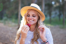 Natural Blonde Woman In Hat Eating Strawberry In Nature