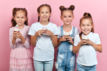 adorable positive little girls holding dessert posing to the camera, happy childhood, party concept, isolated pink background