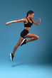 canvas print picture - professional athlete training at sport center, full length side view photo. isolated blue background, studio shot.health and body care, wellness, woman is running to her dream